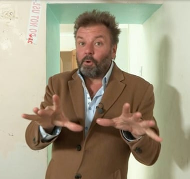 Martin Roberts gesturing self-importantly in a room being renovated