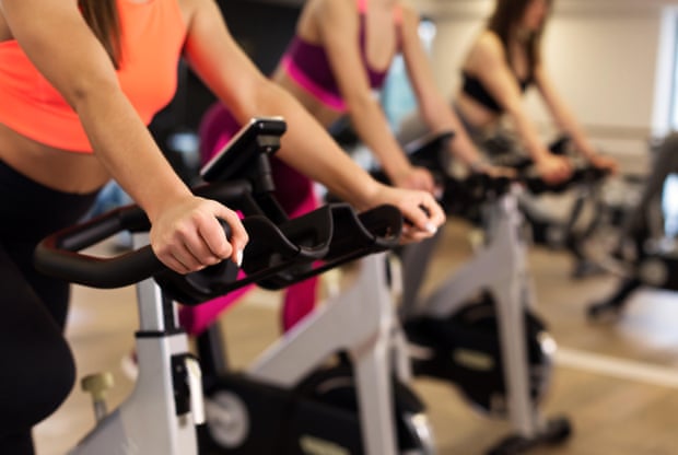 Group of women work out on exercise bikes in a gym.