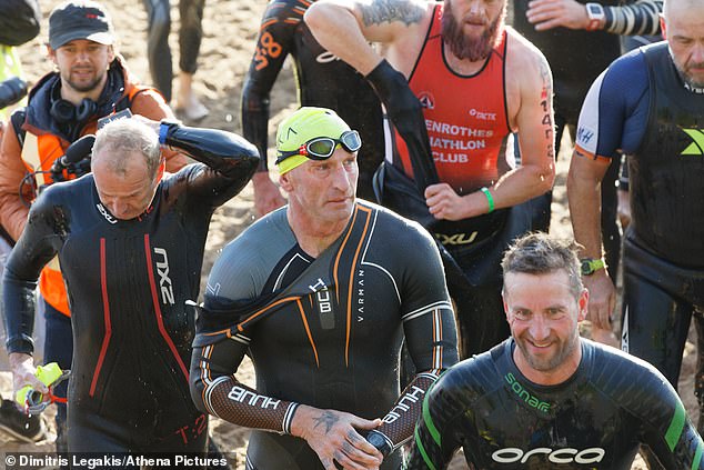 Thomas (pictured centre) is today taking part in the Wales Ironman competition in Tenby. He is pictured emerging from the water this morning after completing the gruelling 2.3-mile swim