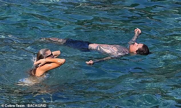 Float: The tattoo artist was seen floating on his back, enjoying the warm waters of the Mediterranean as his girlfriend swam nearby