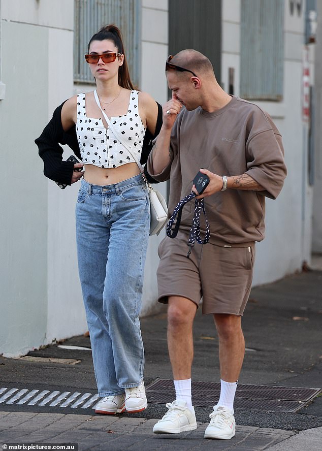 The brunette beauty showed off her flat tummy in a white floral corset top teamed with baggy jeans and sneakers