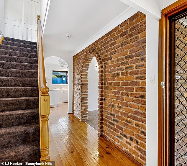 A stylish brick archway at the home sits in-between a large living room and the main hallway