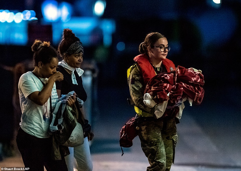 At least four children and a small baby wrapped in a blue blanket were among those led along the walkway by soldiers in camouflage fatigues