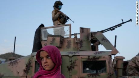 An Afghan girl stands by a Taliban fighter in Paktika province, Afghanistan, Saturday, June 25, 2022. 