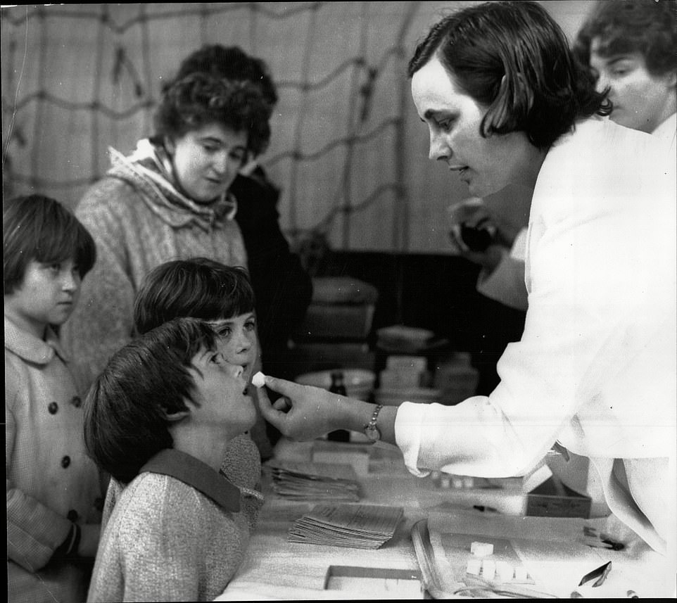 By 1955 researchers at Harvard Medical School, with the support of funds from the March of Dimes non-profit organisation, developed the first effective vaccine against polio — an injectable inactive (killed) polio vaccine (IPV). Pictured: children getting a lump of sugar while getting a polio vaccine at a mobile unit in Blackburn in Lancashire, England in 1965