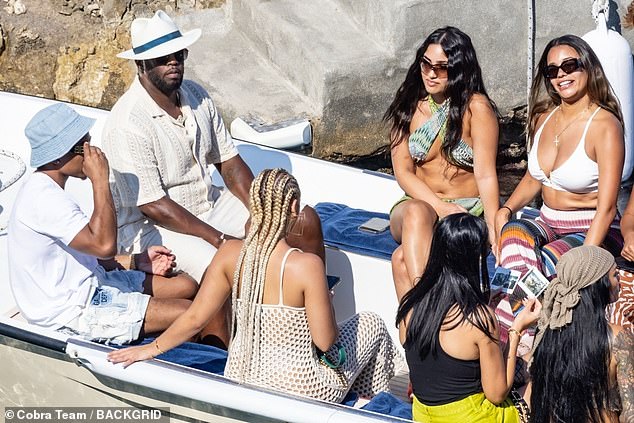 Luxe life: The musician, 52, cur a stylish figure in a cream fedora hat, worn with a summer shirt and chinos as he chatted with a bevy of beauties