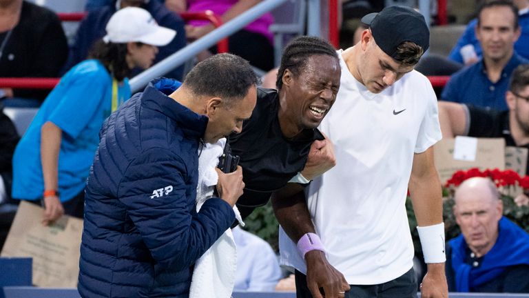 Gael Monfils, of France, is help by his opponent Jack Draper, right, of Britain, and the chair umpire following an injury during the National Bank Open tennis tournament Thursday, Aug. 11, 2022, in Montreal. (Paul Chiasson/The Canadian Press  via AP)