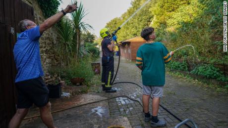 Local residents use garden hoses to assist fire crews tackle a crop fire that swept over farmland and threatened local homes on August 11, 2022 in Skelton, England. 