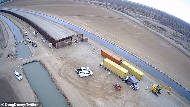 The bright orange and yellow shipping containers are seen being moved into place on Friday