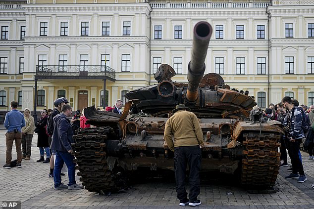 A wrecked Russian tank sits on display in downtown Kyiv as locals admire their soldiers' effort