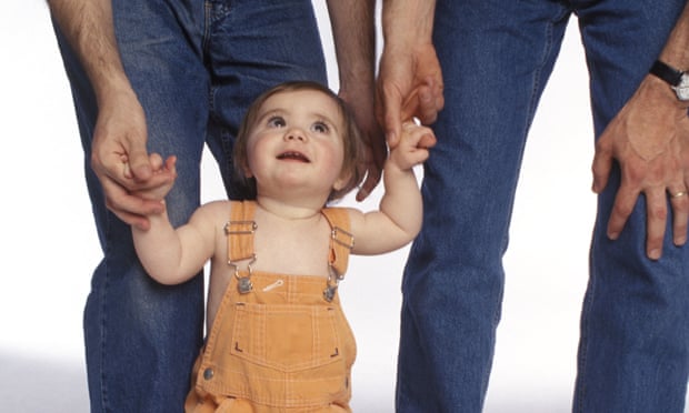 Two men holding a toddler’s hands