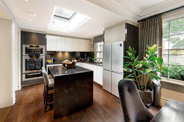 The large open plan kitchen features a black marble island and worktops with a sky light  and large windows to ensure maximum light