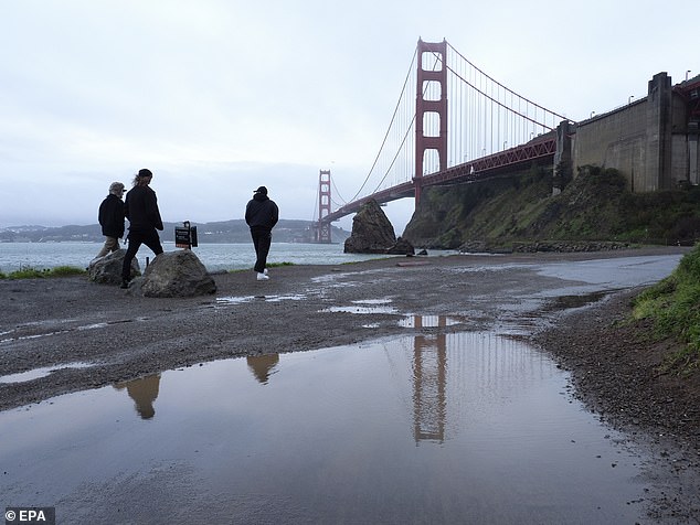 People walking along the water at Fort Baker following an atmospheric rainstorm in Decemeber 2021 that soaked the San Francisco Bay Area