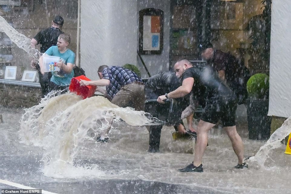 DORSET: Locals and visitors join together to try to clear floodwater away from Seagulls restaurant at West Bay in Dorset yesterday