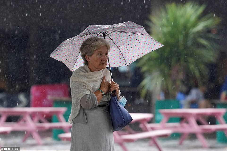 A woman holds an umbrella during a downpour of rain in London today