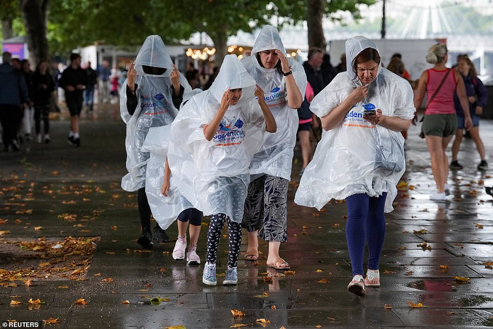 Members of the public in central London wore waterproof overalls as they passed through the rain today