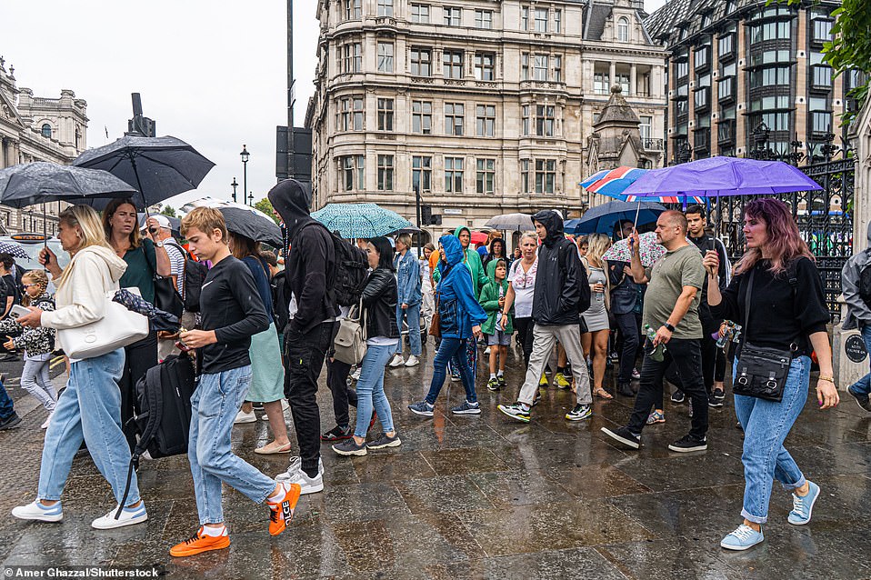 ) Pedestrians shelter under umbrellas in Westminster during heavy rain this afternoon following the prolonged dry spell