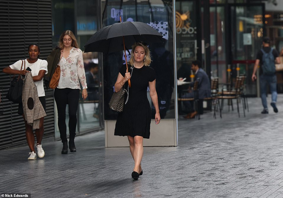 People walk through London near Tower Bridge in the rain yesterday morning as the capital is hit by downpours