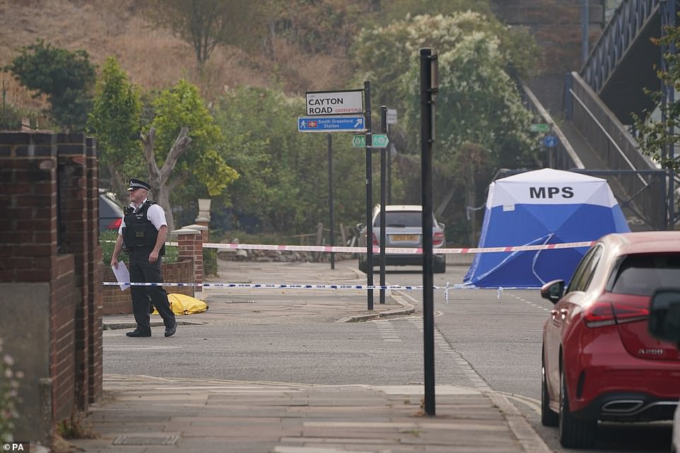 Police at the scene in Greenford, west London, this morning after a man riding a mobility scooter was stabbed to death