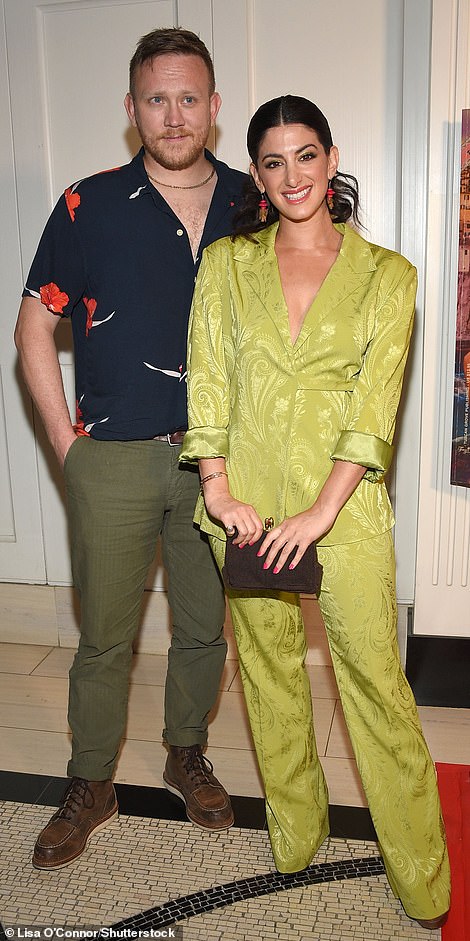 Cute couple: She was joined by her boyfriend M. Miller Davis, who was dressed more casually in a black shirt with red floral designs and olive-colored trousers with brown leather boots