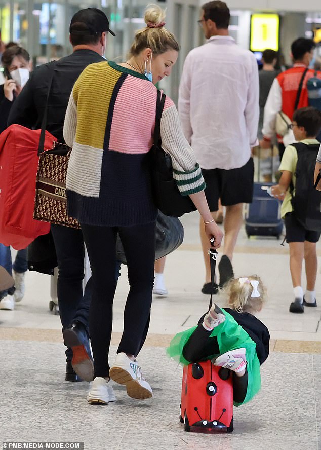 The two-year-old was seen riding on her red ladybug suitcase inside the terminal as mum Jasmine, 38, pulled the bag along behind her