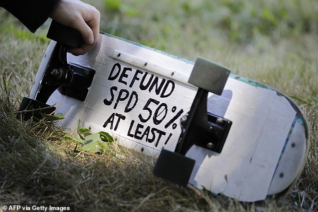 A sign is seen on a protester's skateboard during a Defund the Police march in August 2020