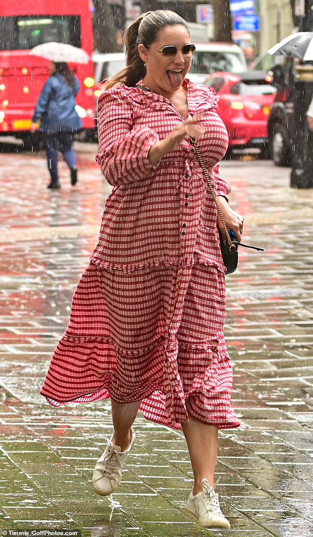 Soaked: Kelly was forced to run through the downpour as she headed inside the building, evening poking out her tongue in a bid to catch a raindrops