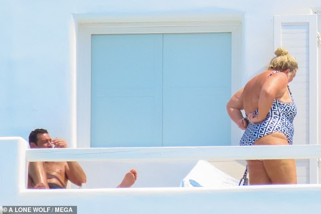 Sensational: Gemma later changed into a blue low-backed swimsuit that flashed plenty of flesh, while Rami sunbathed in a pair of short black shorts