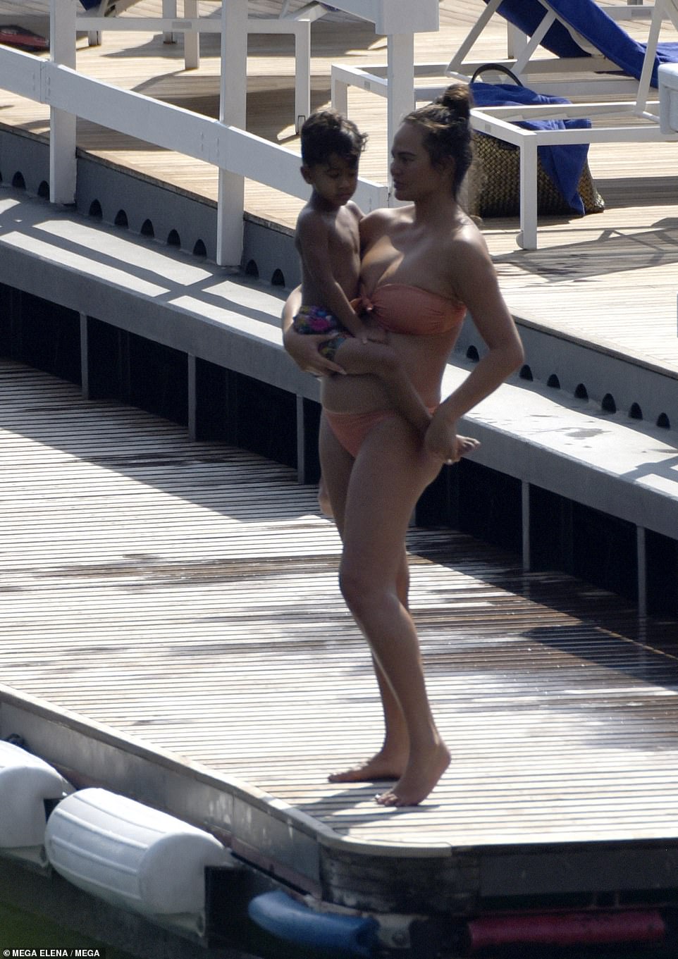 Doting mother: Chrissy bundled her four-year-old son, Miles, into her arms during the pool day