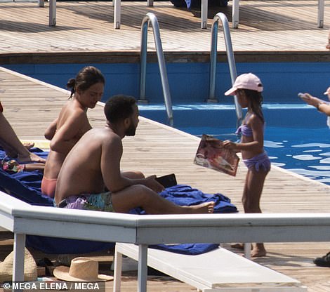 Budding fashionista: Luna, six, was snapped with a fashion magazine as she spoke to her parents by the pool