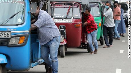 Sri Lankan three-wheeler drivers push their vehicles along the queue near a fuel station in Colombo, Sri Lanka, on Aug. 2. The island nation faces a grave fuel shortage due to the lack of foreign currency.