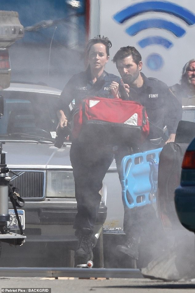 Dakota Johnson and Adam Scott run to the scene of a car crash as they film Madame Web in Boston