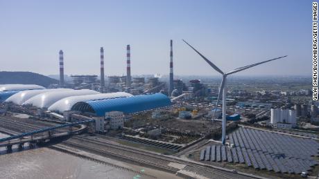 Photovoltaic panels at a solar farm and wind turbines near a coal fired power station in Jiaxing, Zhejiang province, China, on Friday, March 11, 2022.