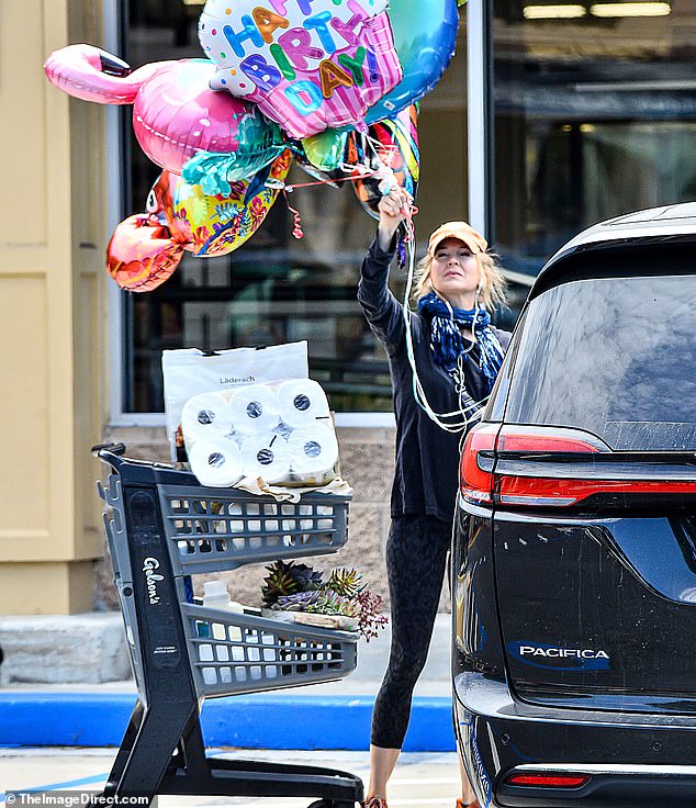 Renee Zellweger looks overwhelmed pushing a grocery cart as she picks up balloons