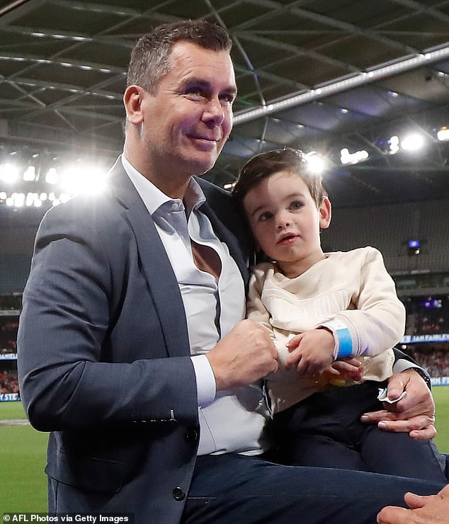 Wayne Carey cradles his rarely-seen son as he attends AFL game