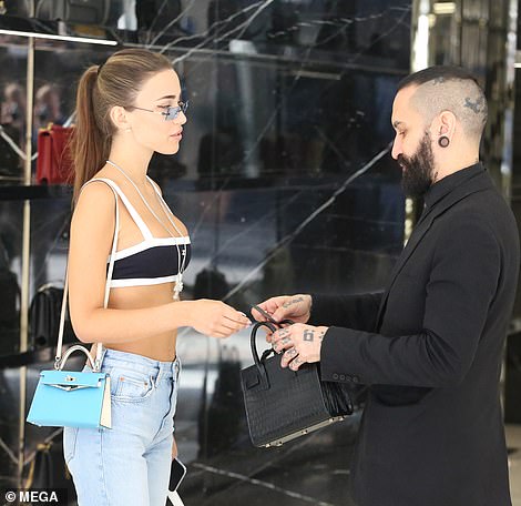 Big spender: While she also had a closer look at a YSL black croc-skinned piece - with a male member of staff helping her out with the shopping