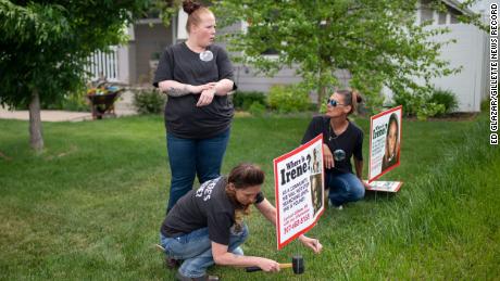 Lacey Ayers talks to Stacy Koester, left, and Melissa Bloxom as they place signs with an image of Irene Gakwa in a yard in Gillette, Wyoming. Gakwa lived with her boyfriend next door. 