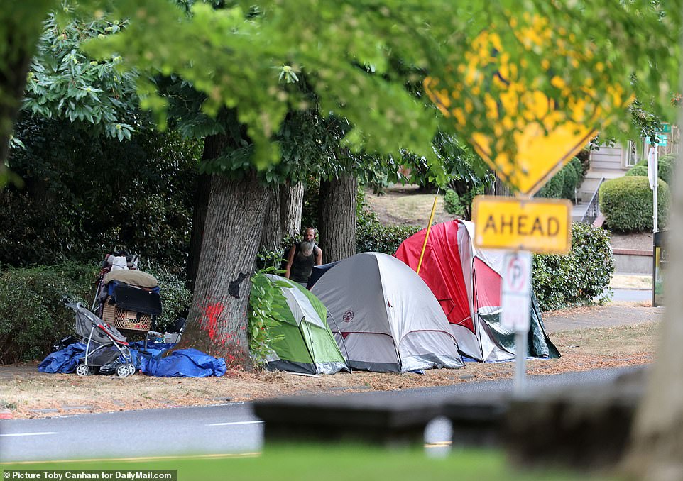 A homeless man is seen next to tents, a shopping cart and stroller full of belongings and trash. Homeless encampments have been popping up along residential streets in several Portland neighborhoods