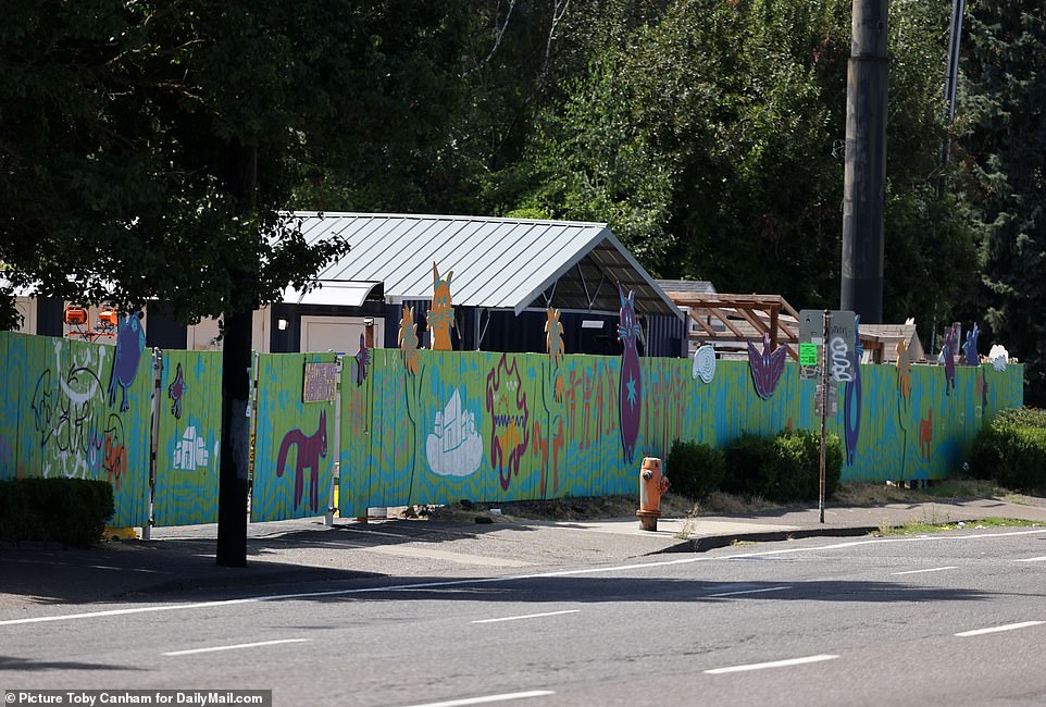 The BIPOC village can be seen over the green fence that stands between the shelters and the street