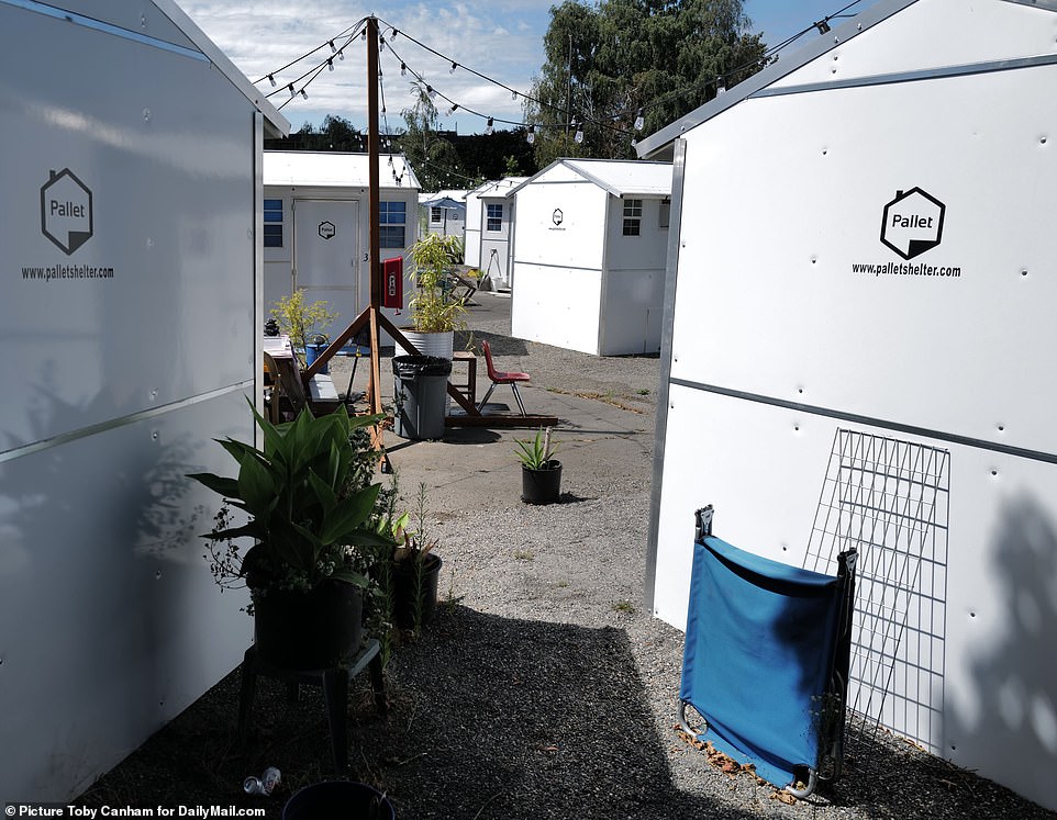 White structures fill a lot near the BIPOC village homeless encampment site near the Crowne Plaza hotel