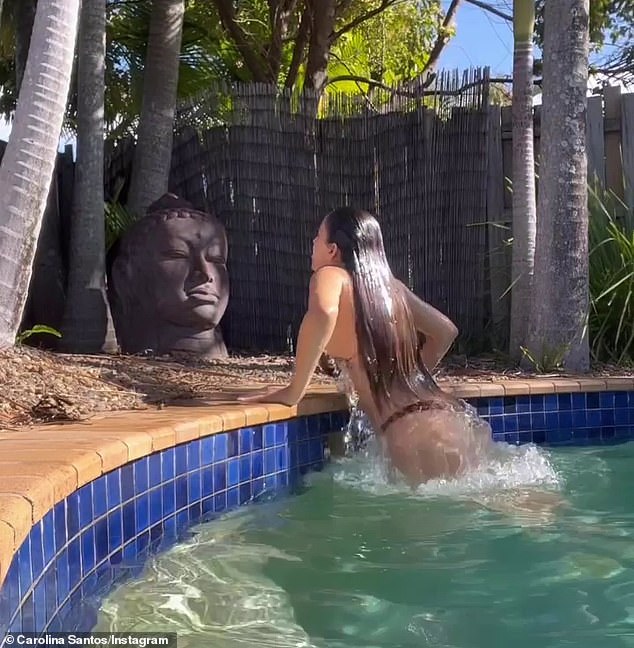 Her bikini top struggles to contain her ample assets as she climbs out of the pool dripping wet