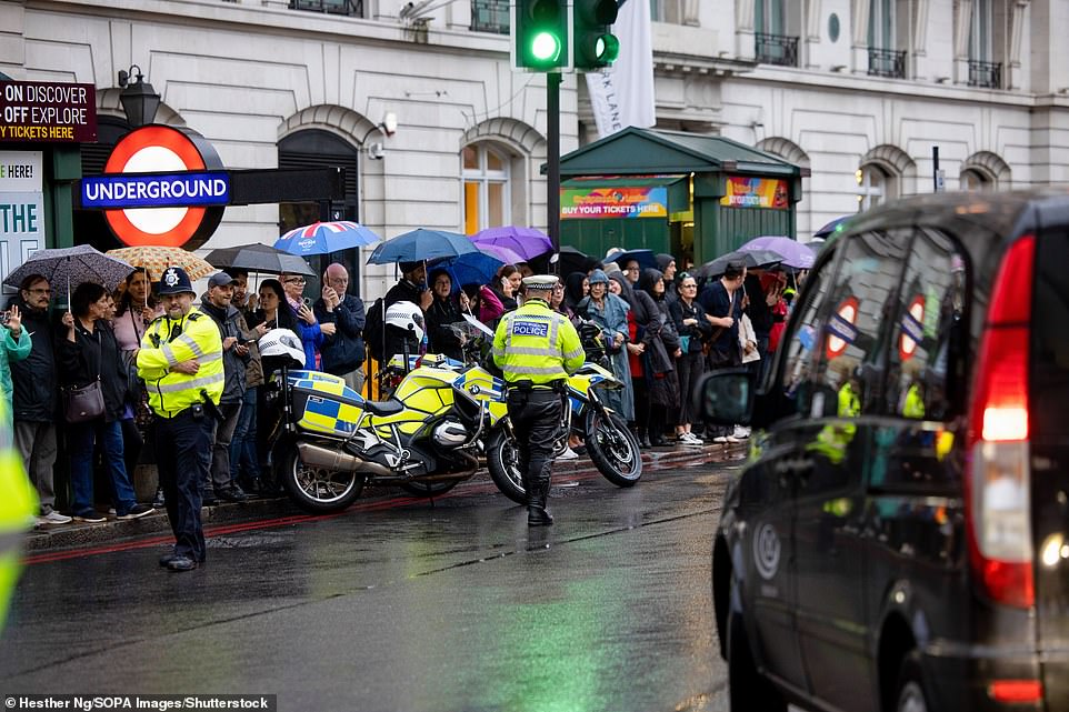 Met Police Officers seen maintaining order while thousands of people wait on the route of the state hearse of Queen Elizabeth II to bid their final farewell to Her Majesty.