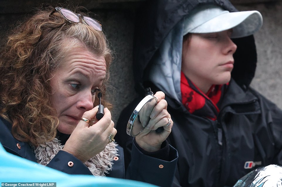 A woman puts on makeup on Wednesday morning as she sits in the queue for the Queen's lying in state