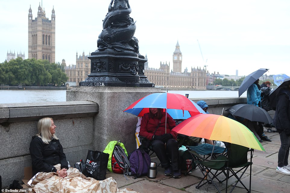 Two women speak to each other in the queue along the bank of the Thames ahead of the Queen's lying in state