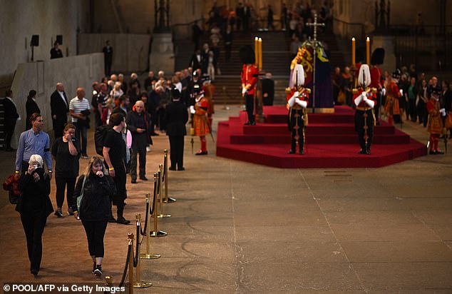 Members of the public pay their respects as they pass the coffin of Queen Elizabeth II at the Palace of Westminster this evening