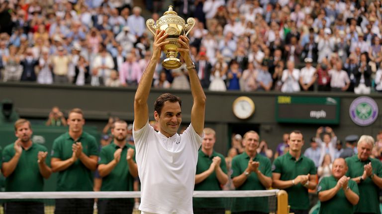 Roger Federer is applauded by ground staff as he holds the trophy after defeating Croatia&#39;s Marin Cilic to win the Men&#39;s Singles final match