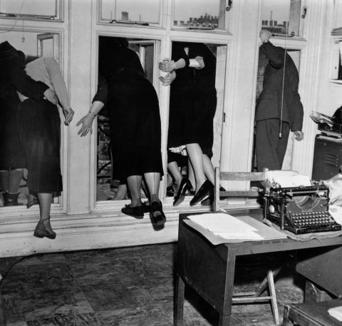 Workers look out of office windows to watch the funeral procession on February 15, 1952.