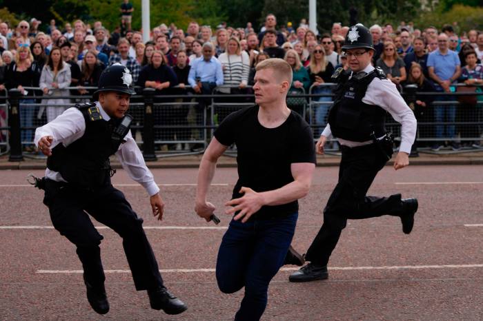 Police officers chase a man before King Charles III arrives