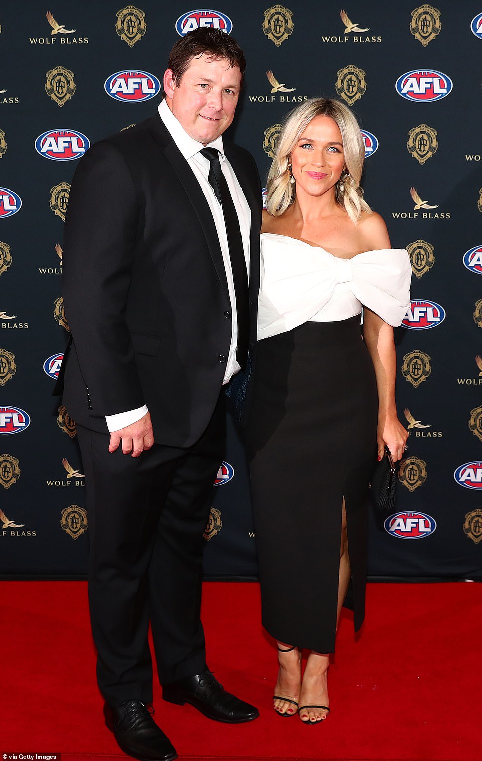 Sarah Cumming, the glamorous wife of Gold Coast Suns coach Stuart Dew, made a statement in a monochrome dress with an oversized bow and daring thigh split. However the blonde beauty was caught wearing what appeared to be the same exact same dress as Rebecca Demlakian - the girlfriend of Greater Western Sydney Giants star Stephen Coniglio