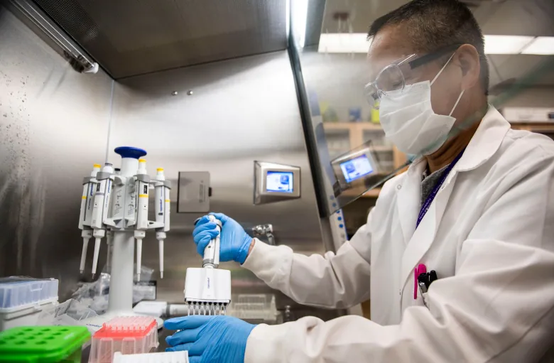 A researcher in a lab coat operates equipment.